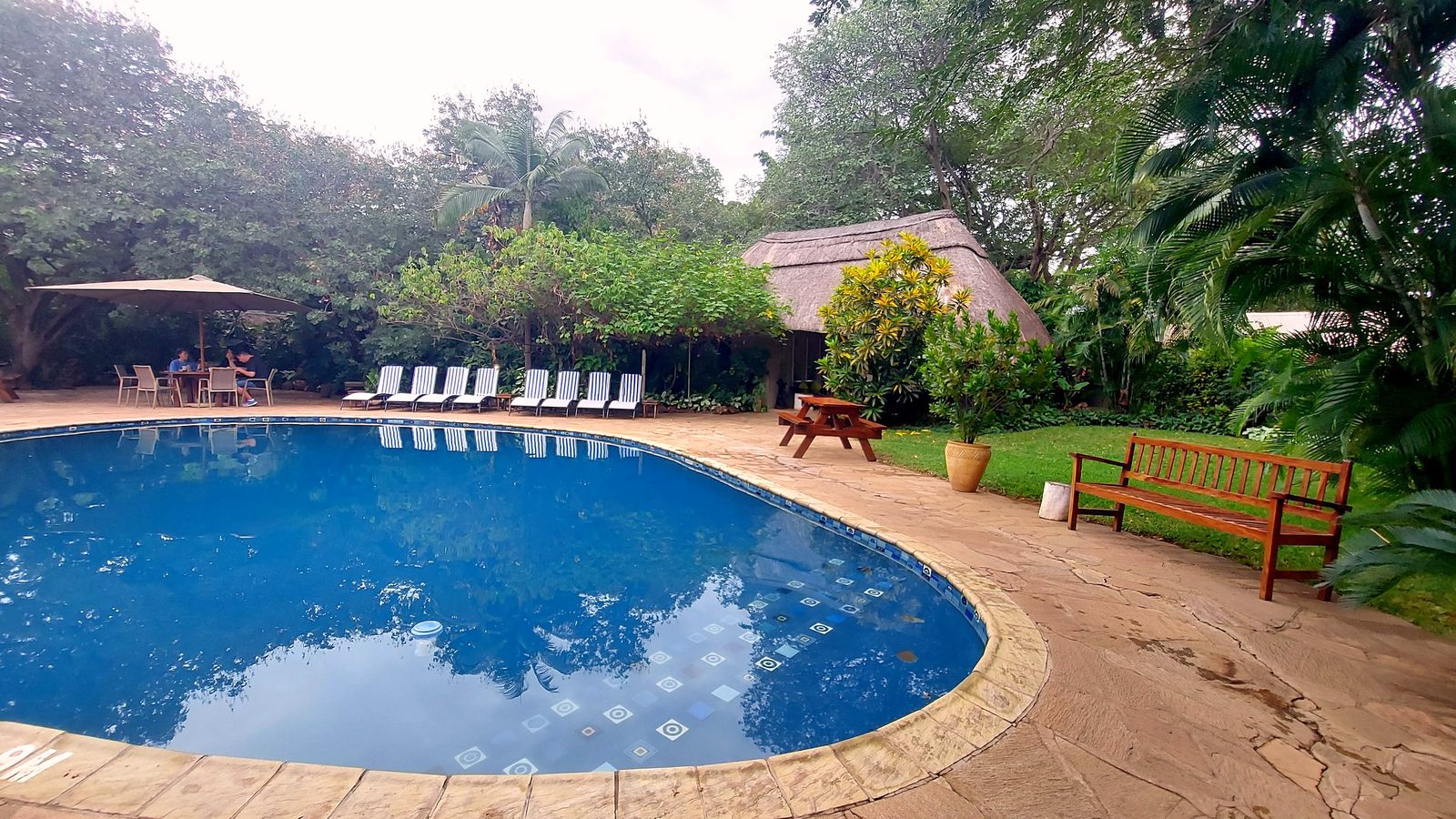 The pool, loungers and thatched building